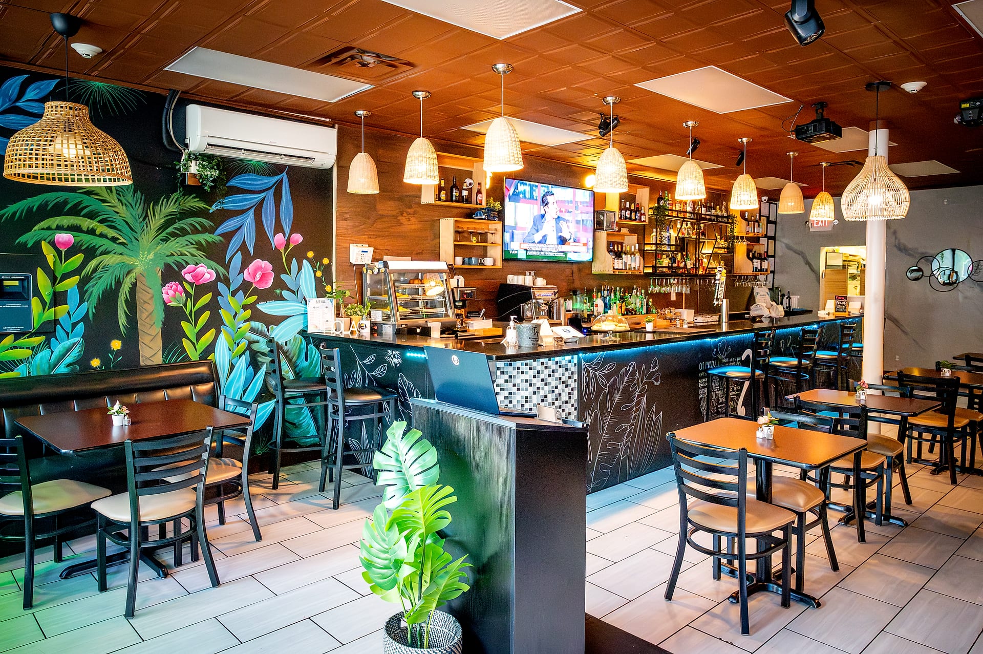 Dining room interior at Delicias Colombianas, tables and tropical palm mural