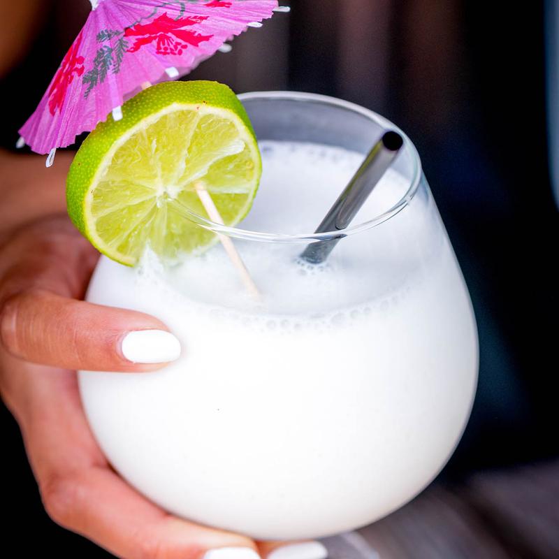 Frozen piña colada with paper umbrella and lime
